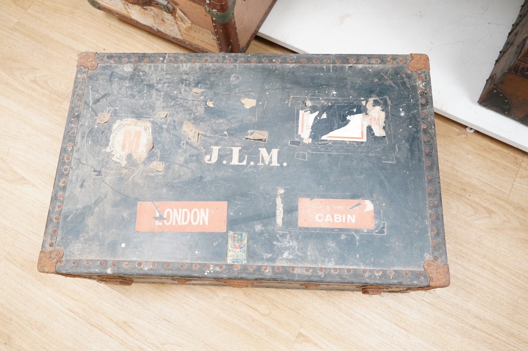 A collection of vintage luggage comprising four early 20th century bound travelling trunks and three kit bags